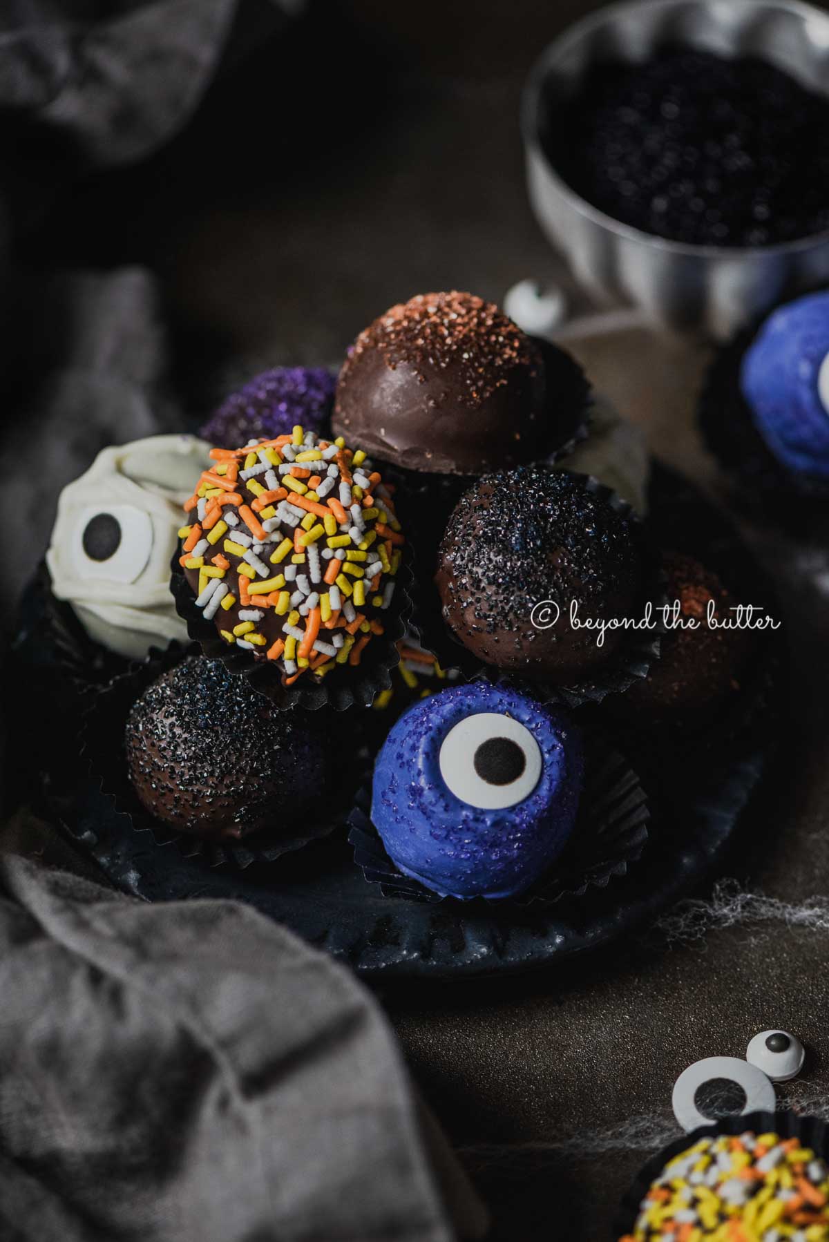 Plate of stacked homemade chocolate truffles with more around it on dark background | All Images © Luyiz®