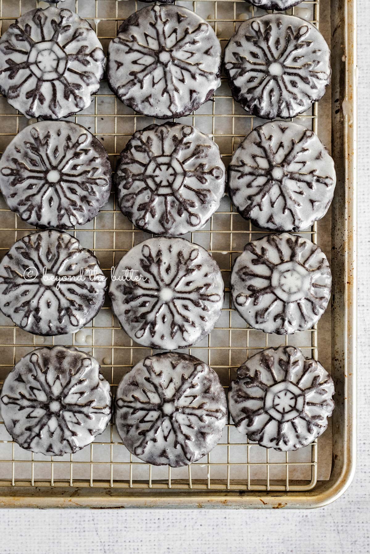 Overhead image of homemade oreo snowflake cookies on a baking sheet and wire cooling rack | All Images © Luyiz®
