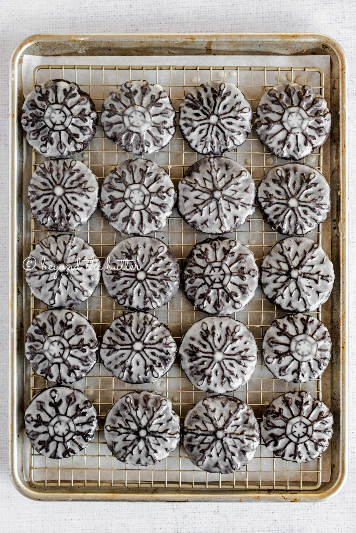 Overhead image of homemade oreo snowflake cookies on a baking sheet and wire cooling rack | All Images © Luyiz®