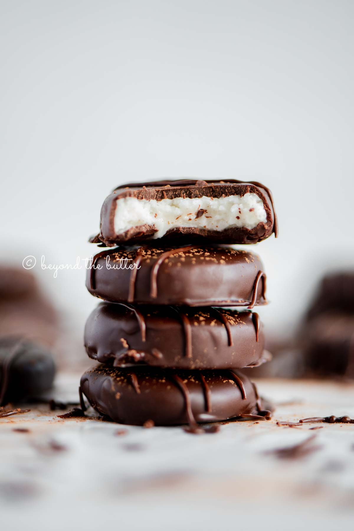 Stack of 4 peppermint patties surrounded by more peppermint patties with white background.