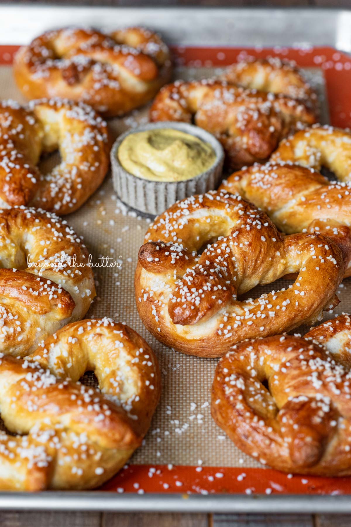 Homemade soft pretzels on a silicone lined baking sheet ready for dipping into spicy mustard | © Luyiz®
