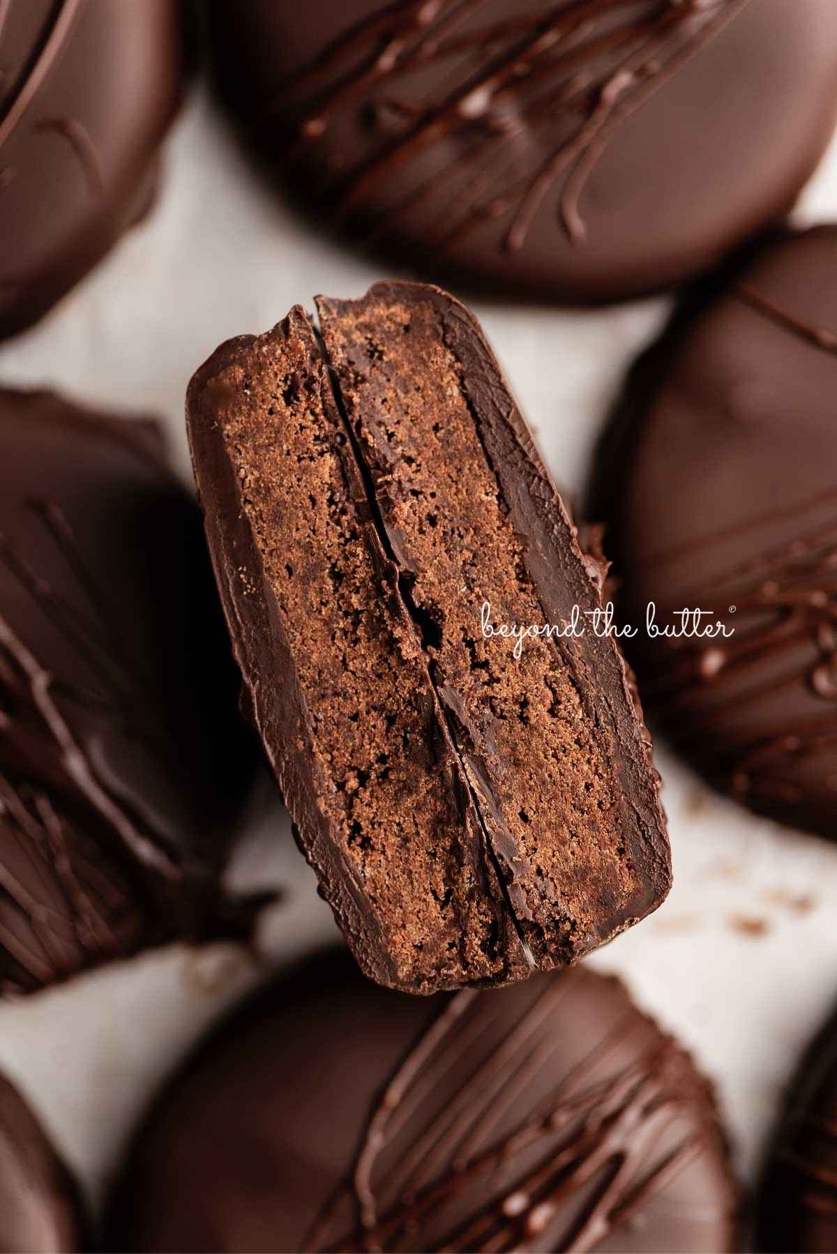 Homemade thin mints on a wax paper lined baking sheet with center cookie cut in half.