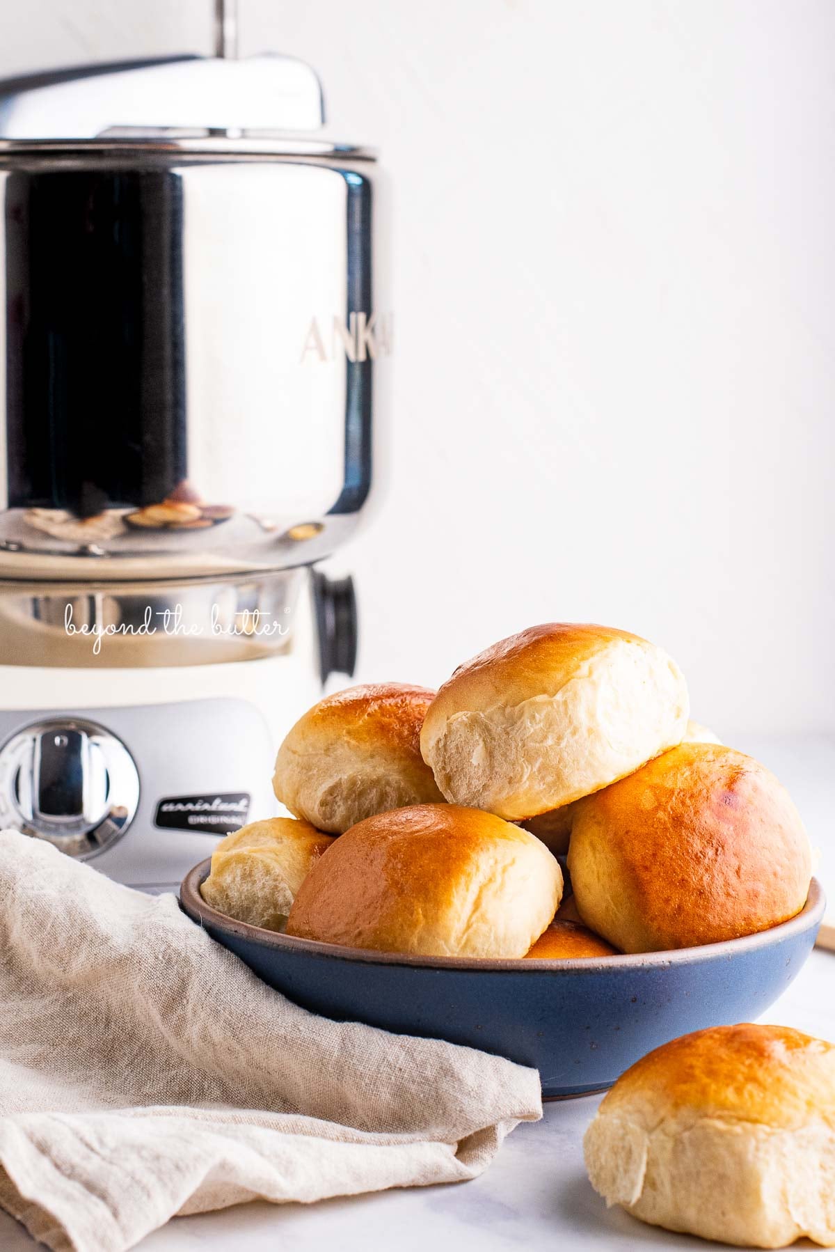 Honey butter dinner rolls in a blue ceramic bowl made with the Ankarsrum Original Mixer | © Luyiz®