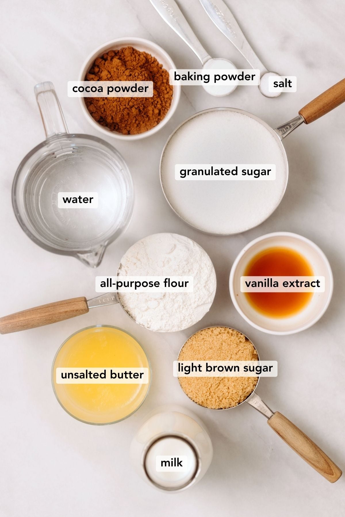 Ingredients needed to make hot fudge chocolate pudding cake displayed on a white marbled background.