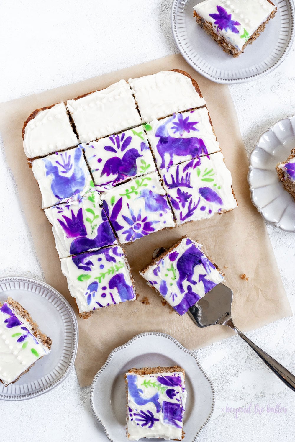 Hummingbird Sheet Cake with White Chocolate Cream Cheese Frosting | Overhead photo of Hummingbird Sheet Cake that's topped with a white chocolate frosting, and stenciled using purple and green frosting | Image and Copyright Policy: © Luyiz, LLC.