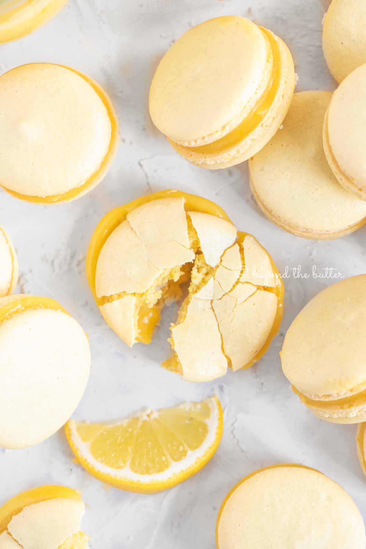 Overhead image randomly placed lemon macarons with the center macaron broken apart | All Images © Luyiz™