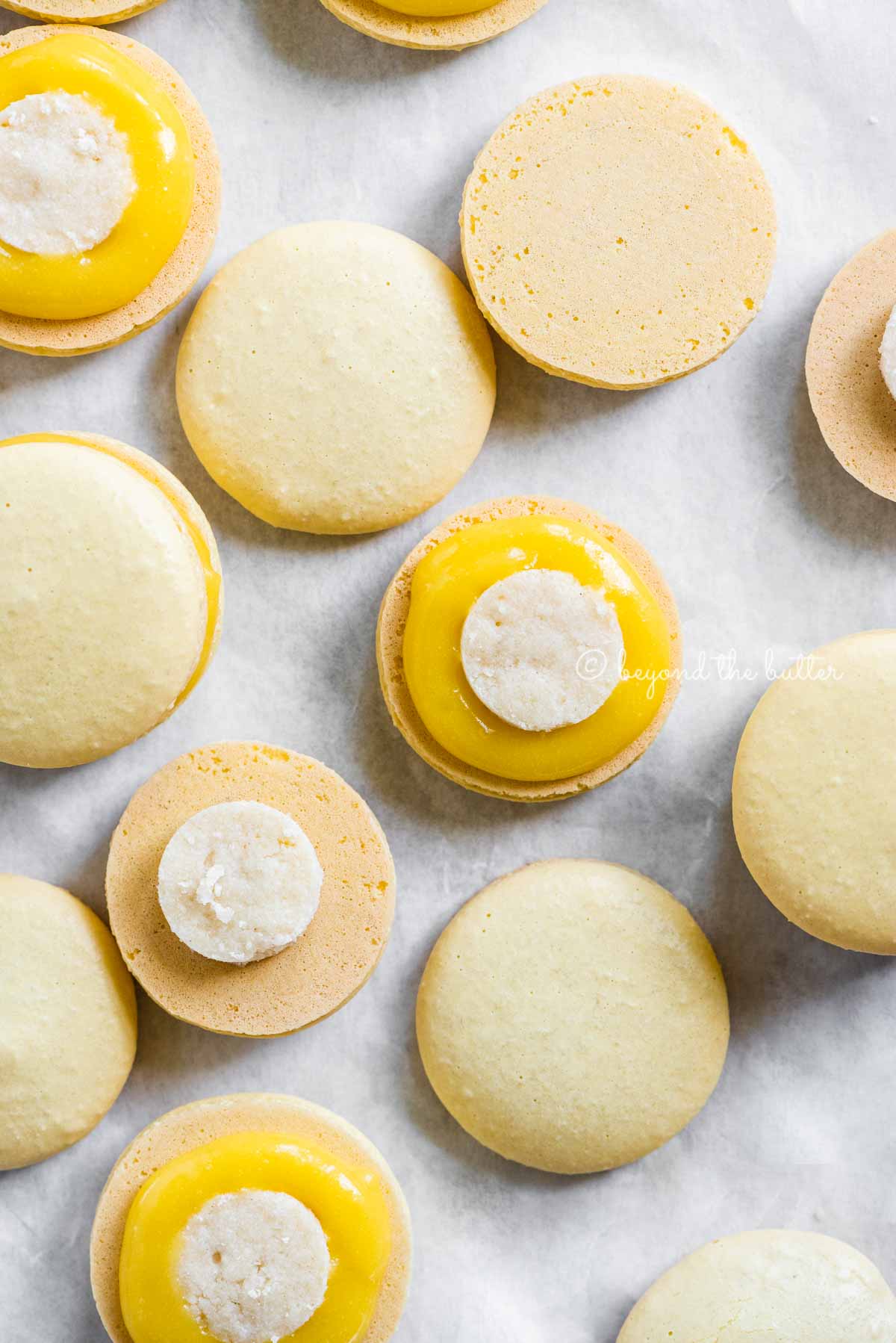 Overhead image of lemon bar macarons half opened topped with shortbread crust centers and lemon curd filling | All Images © Luyiz™