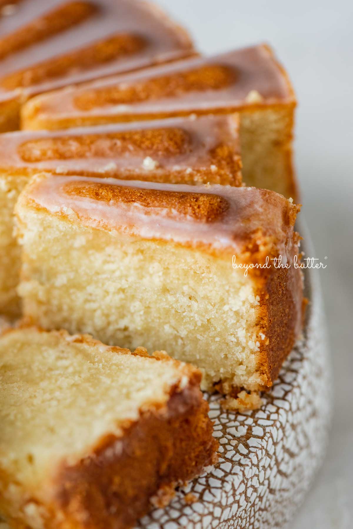 Sliced lemon cream cheese pound cake with a lemon glaze on a cake stand | © Luyiz®