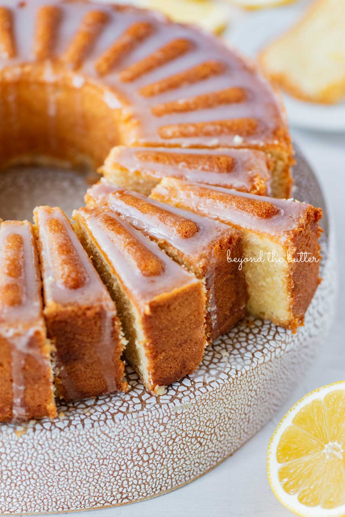 Sliced lemon cream cheese pound cake with a lemon glaze on a cake stand | © Luyiz®