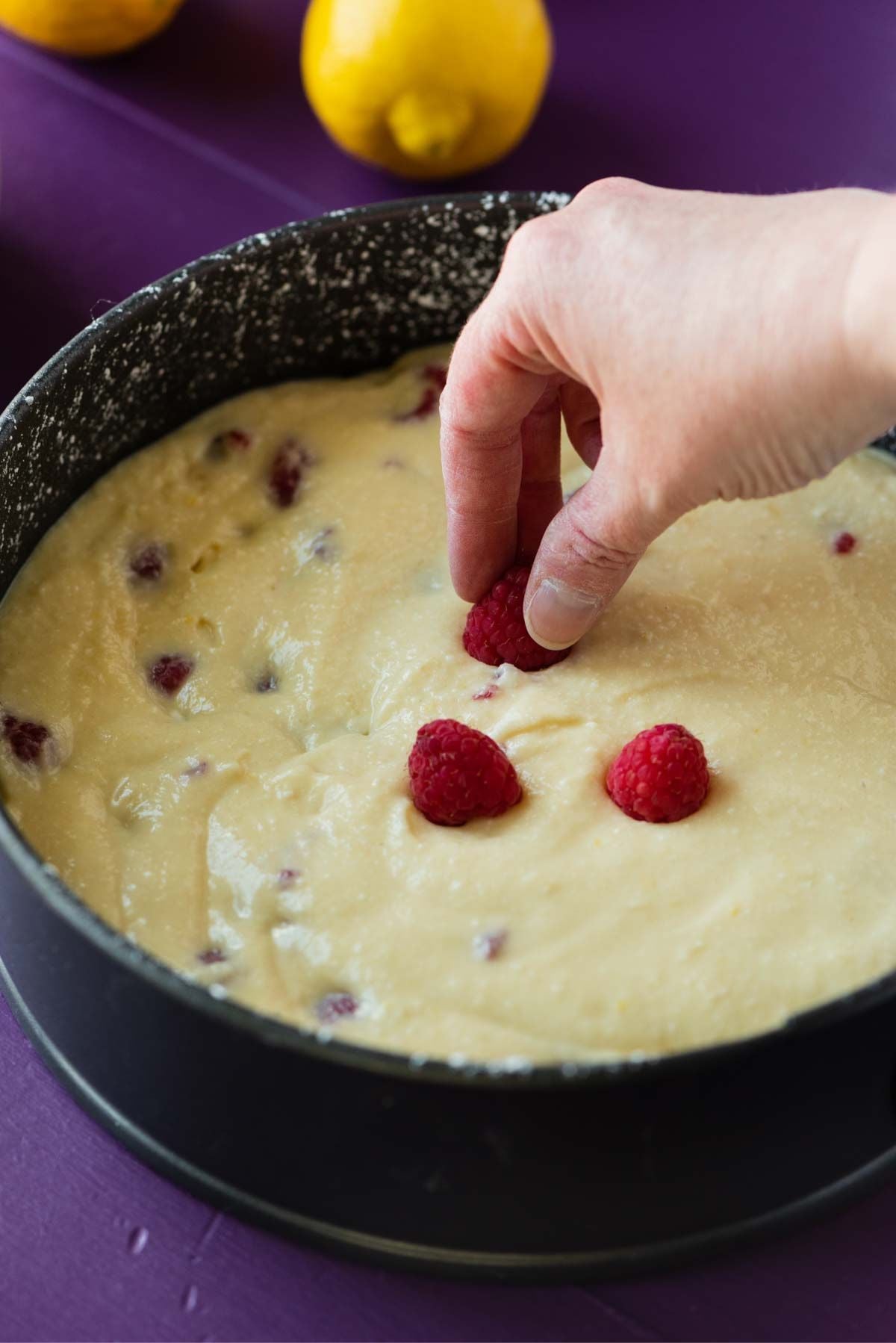 Topping the lemon raspberry ricotta cake with fresh raspberries before baking.