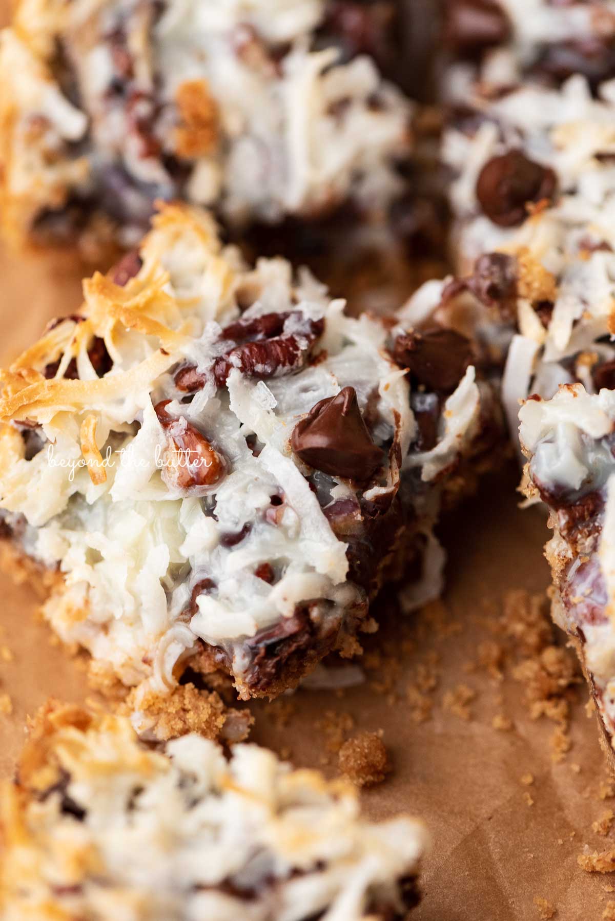 7 layer magic cookie bars on brown parchment paper | © Luyiz®