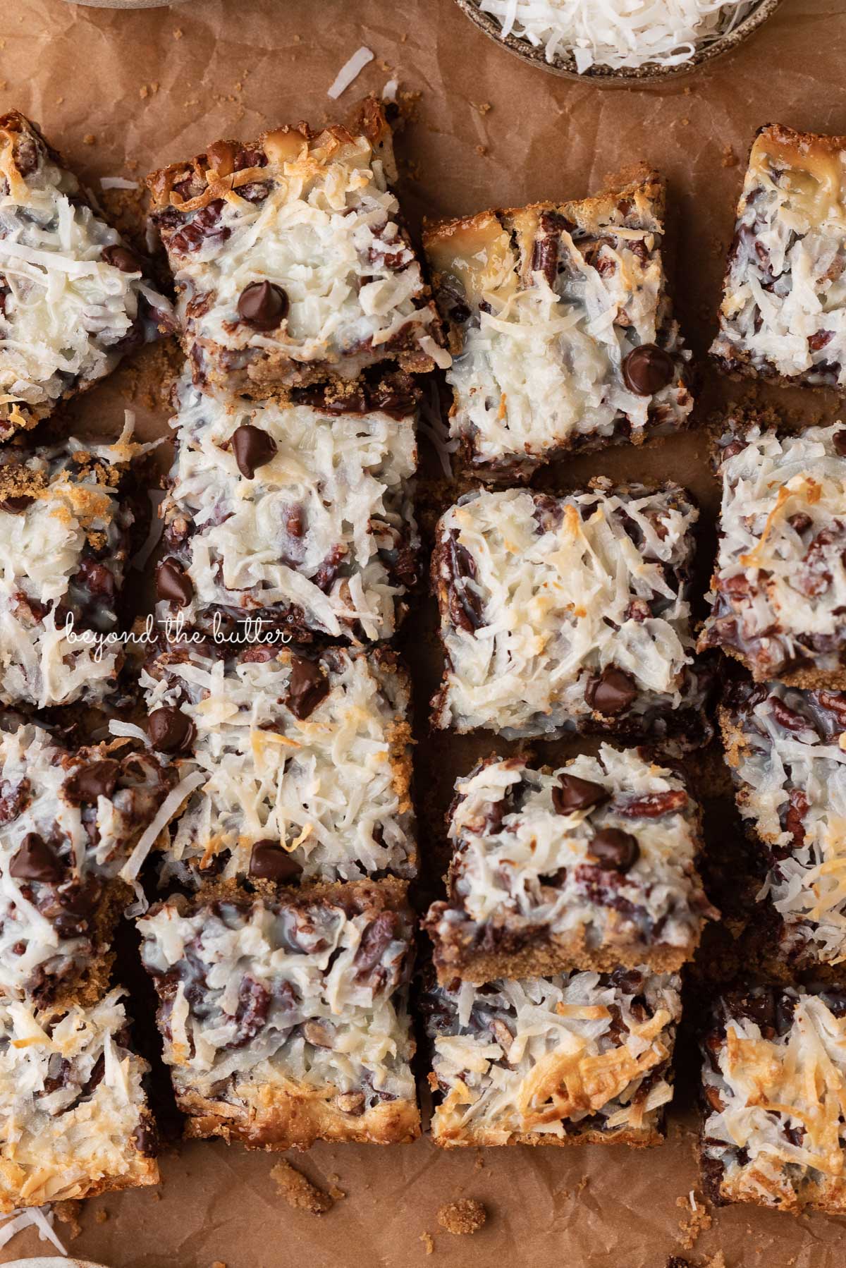 7 layer magic cookie bars on brown parchment paper | © Luyiz®