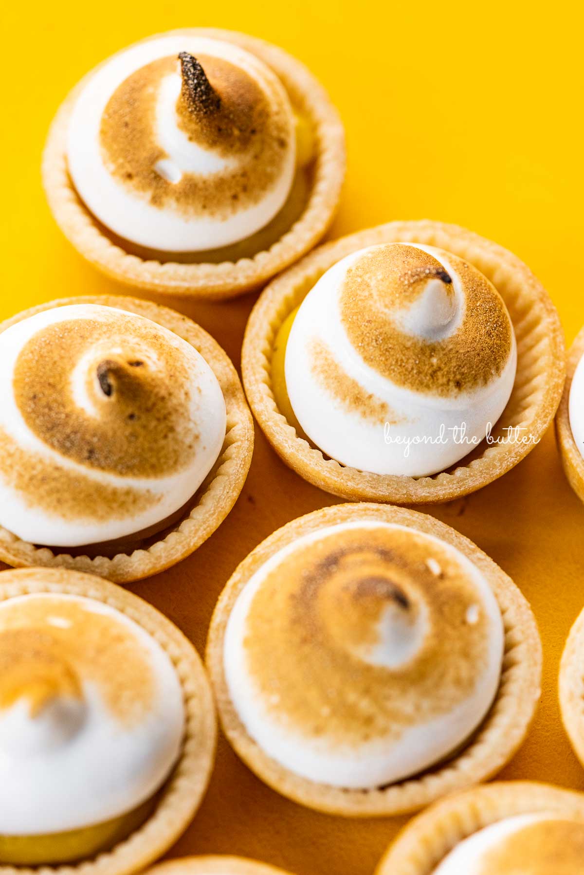 Angled image of mini lemon meringue pies on a yellow background | © Luyiz®