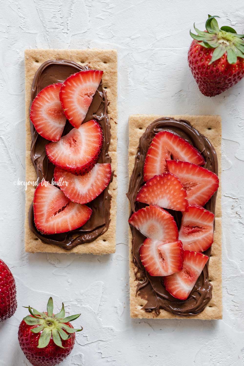 Image of strawberries and nutella spread over top of 2 graham crackers | All Images © Luyiz®