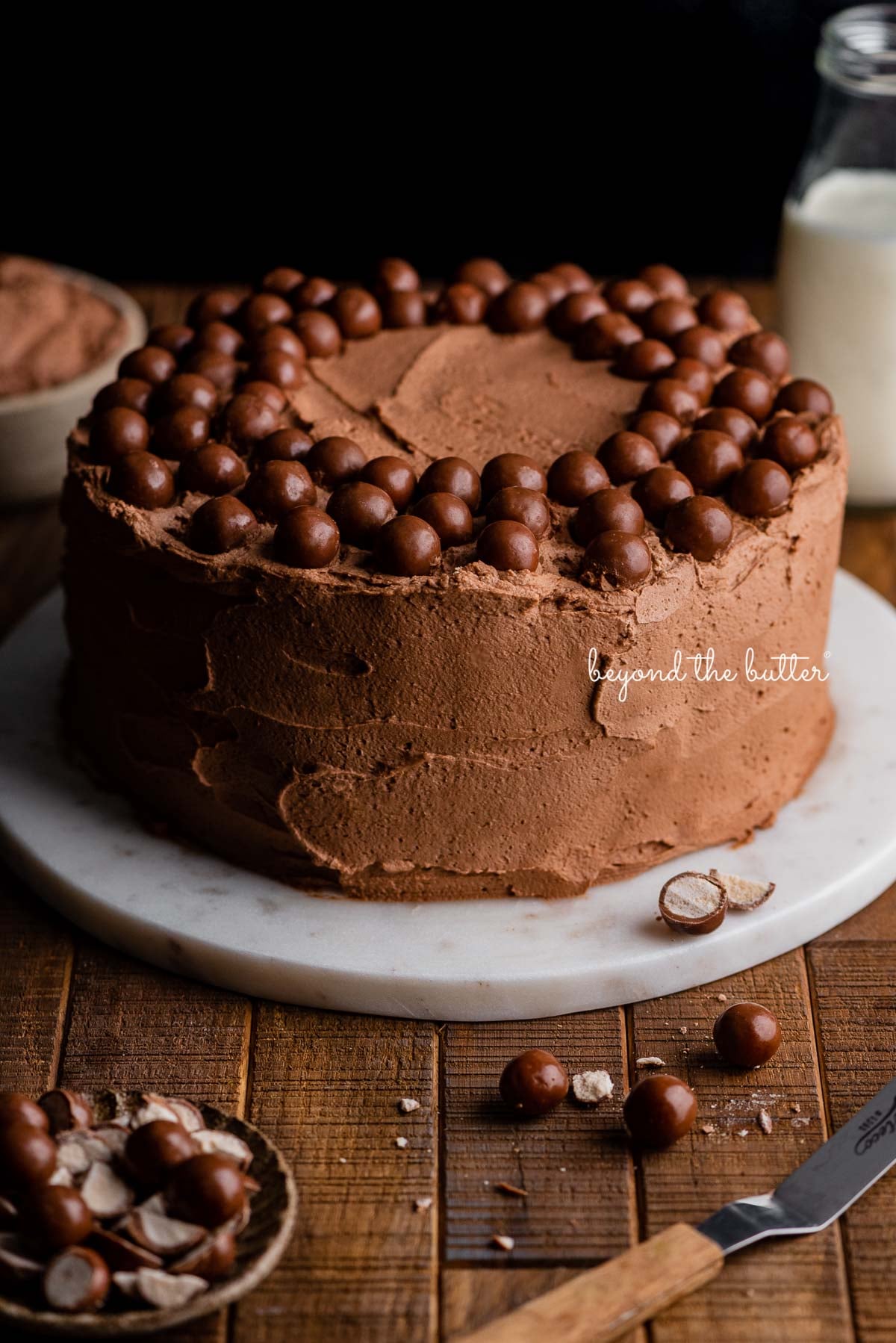 Malted chocolate whipped cream frosted banana cake on a marble cake stand and dark wood background | © Luyiz®