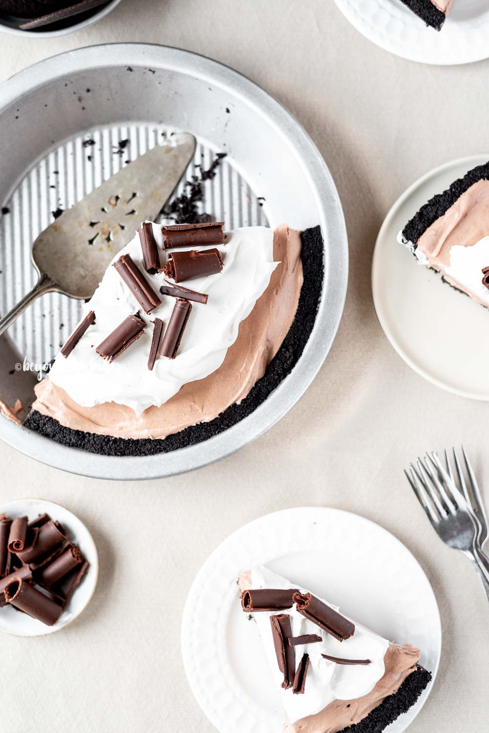 Overhead image of sliced no-bake chocolate cream pie with slices of pie on dessert plates next to it | All Images © Luyiz™