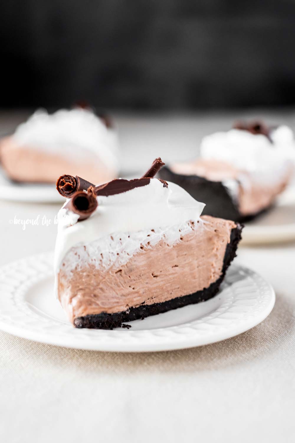 Slice of no-bake chocolate cream pie with chocolate wafer crust on dessert plates | All Images © Luyiz™