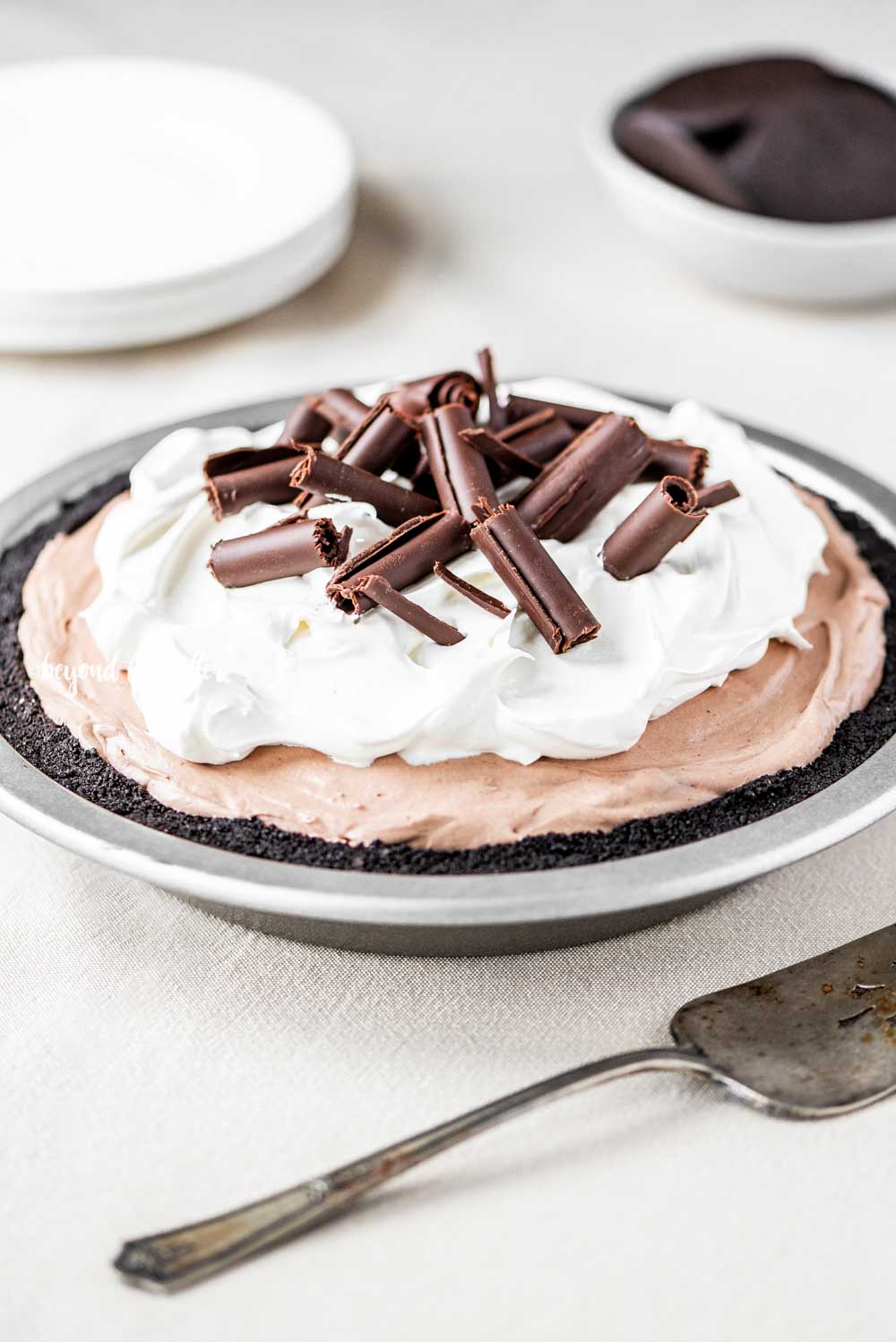 Angled image of no-bake chocolate cream pie with chocolate wafer crust and garnished with Cool Whip and chocolate curls | All Images © Luyiz™