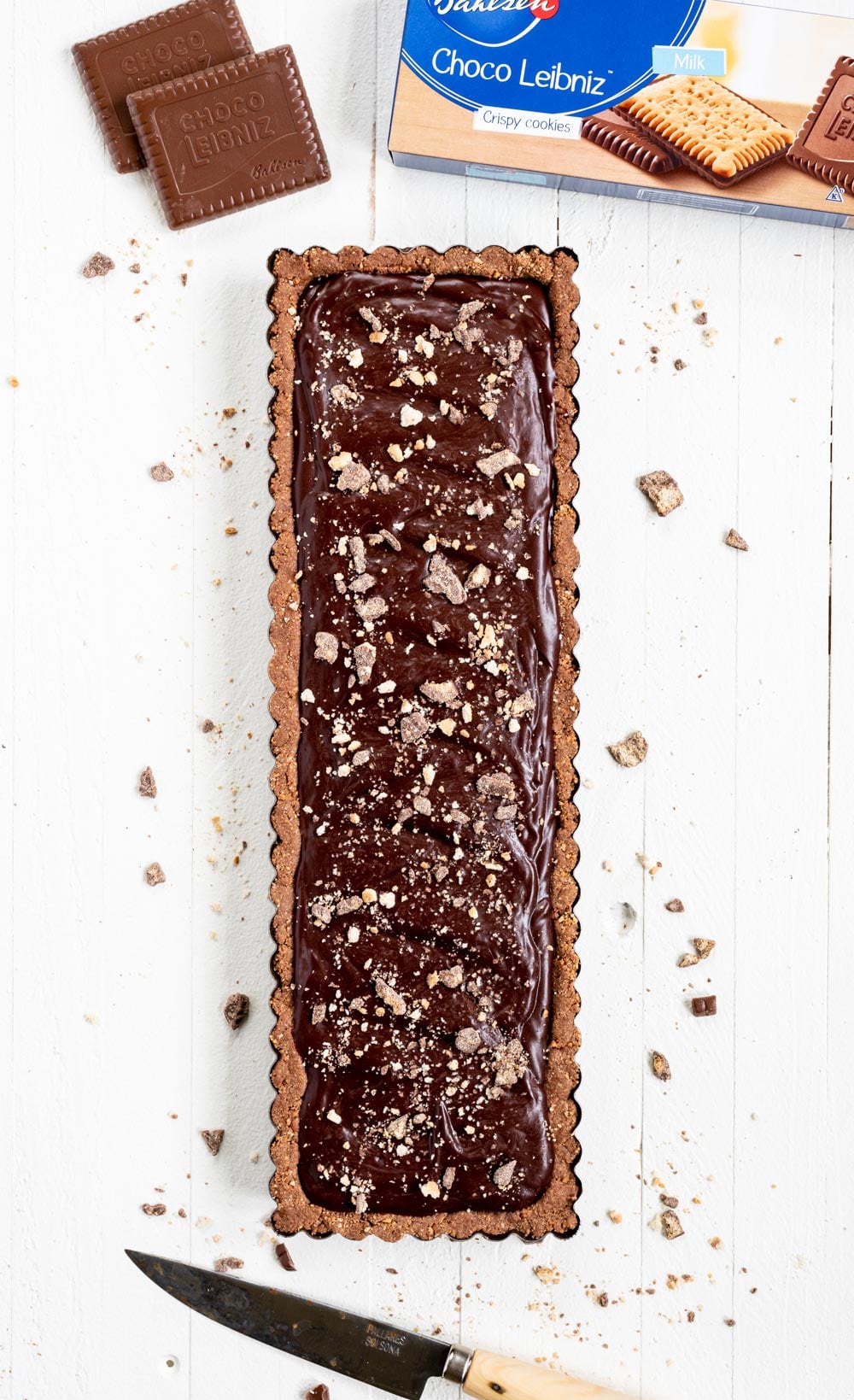 No-bake Dark Chocolate Tart |Overhead image of No-Bake Dark Chocolate Tart with a box of the cookies above it and a cutting knife below | Image and Copyright Policy: © Luyiz, LLC