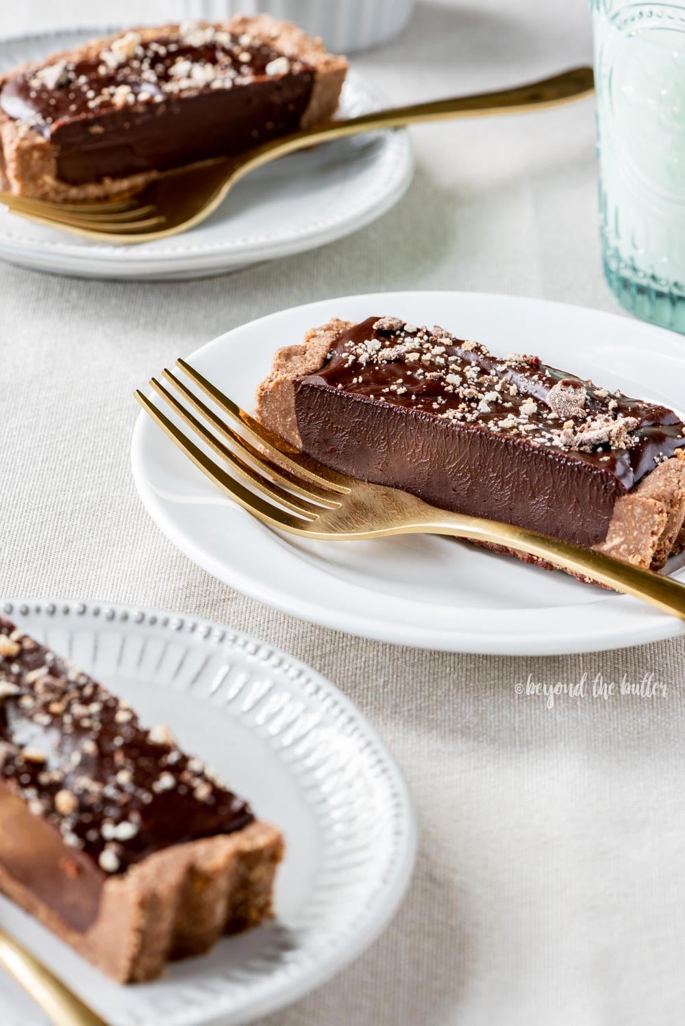 No-bake Dark Chocolate Tart | Slices of no-bake dark chocolate tart on dessert plates with forks and a glass of milk | Image and Copyright Policy: © Luyiz, LLC