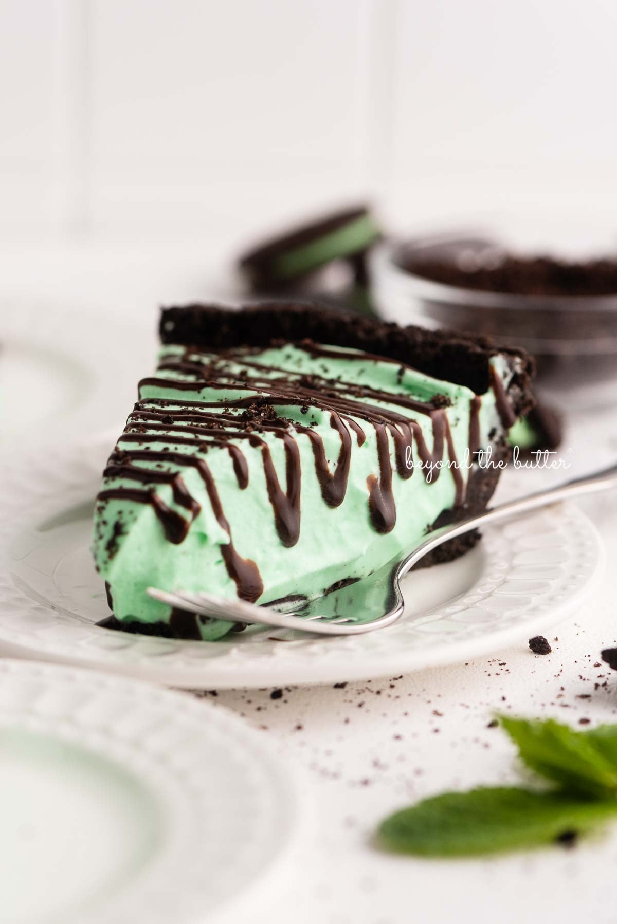 Dessert plates with slices of no bake mint chocolate pie with chocolate syrup drizzled over the top | © Luyiz®