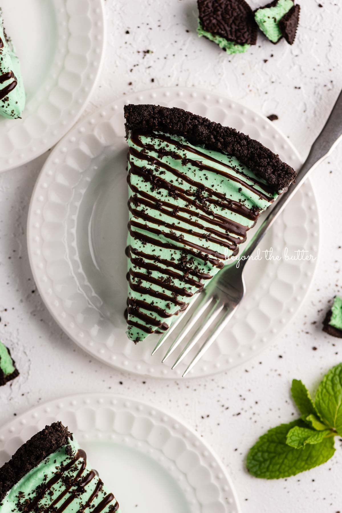 Dessert plates with slices of no bake mint chocolate pie with chocolate syrup drizzled over the top | © Luyiz®