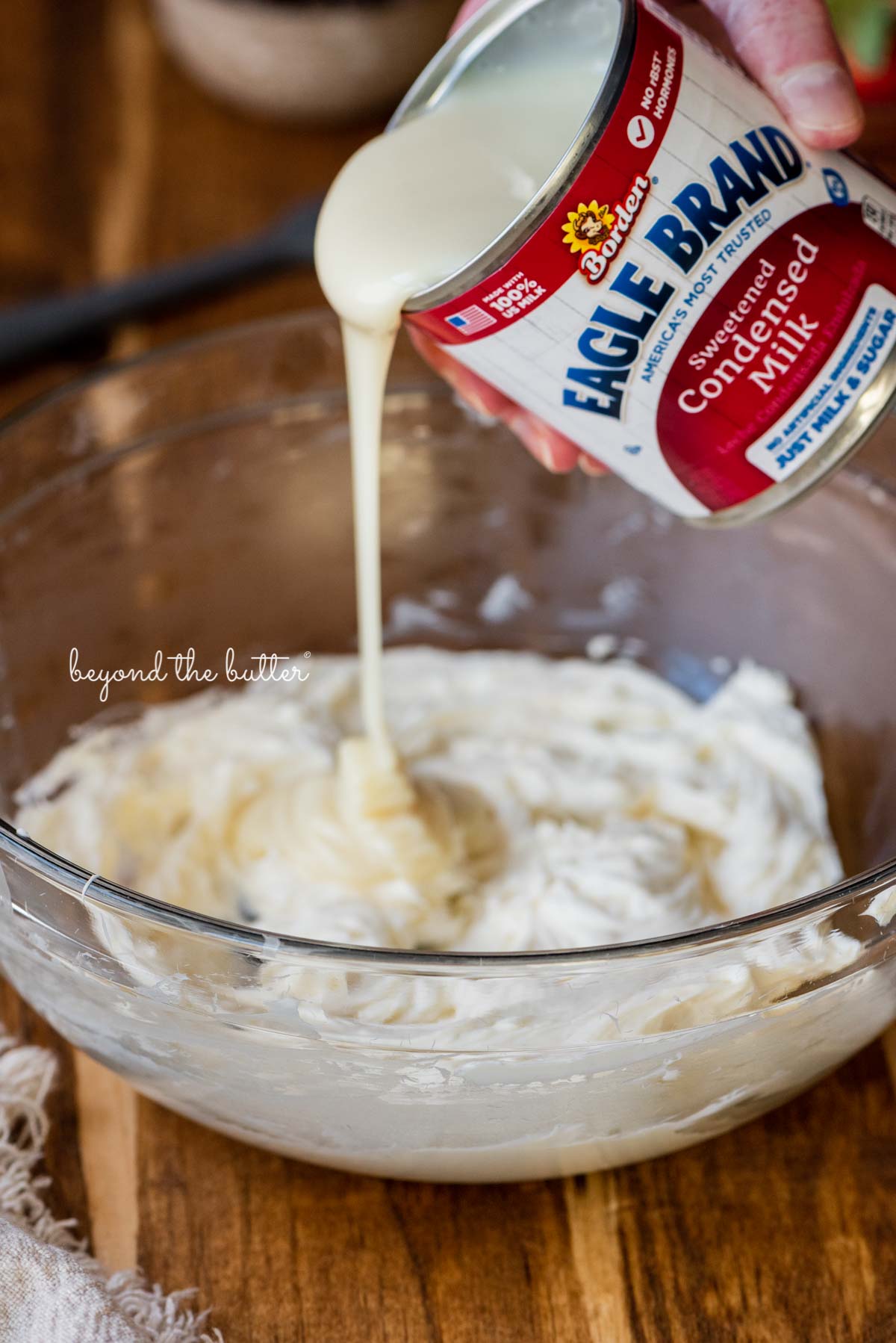 Pouring Eagle Brand® sweetened condensed milk into the mixing bowl with cream cheese | All images © Luyiz®
