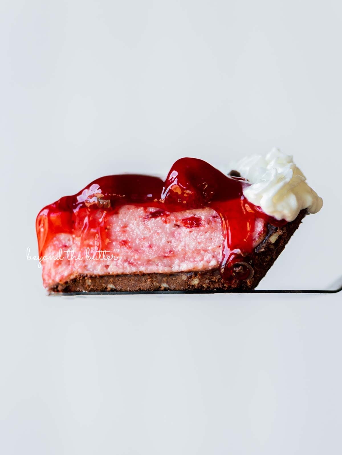Singel slice of no bake strawberry chocolate pie resting on a pie server with a white background | All images © Luyiz®