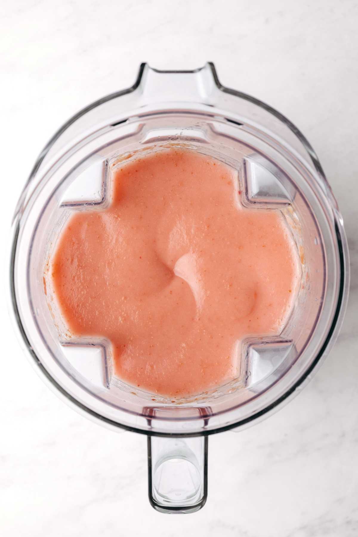 Blended cortland apples in a blender with the lid off on a white background.
