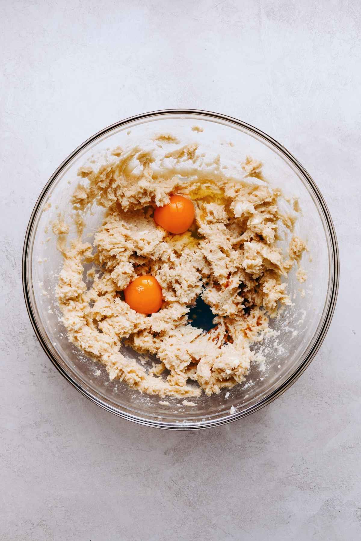 Wet ingredients blended together in a glass mixing bowl with egg yolks and vanilla extract on top.