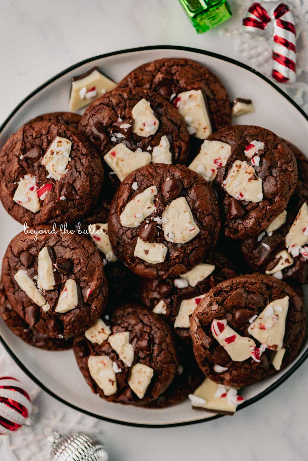 Plate full of peppermint bark brownie crinkle cookies with ornaments around the plate | © Luyiz®