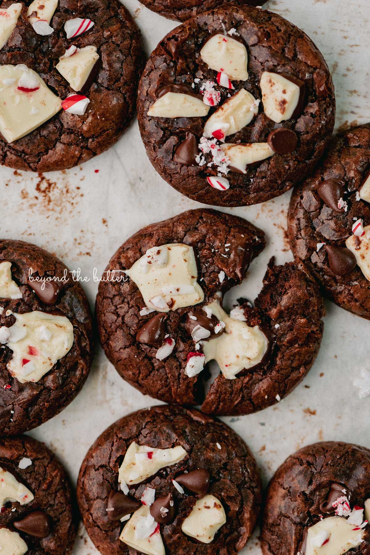 Just baked peppermint bark brownie crinkle cookies on a parchment paper lined baking sheet | © Beyond the Buter®