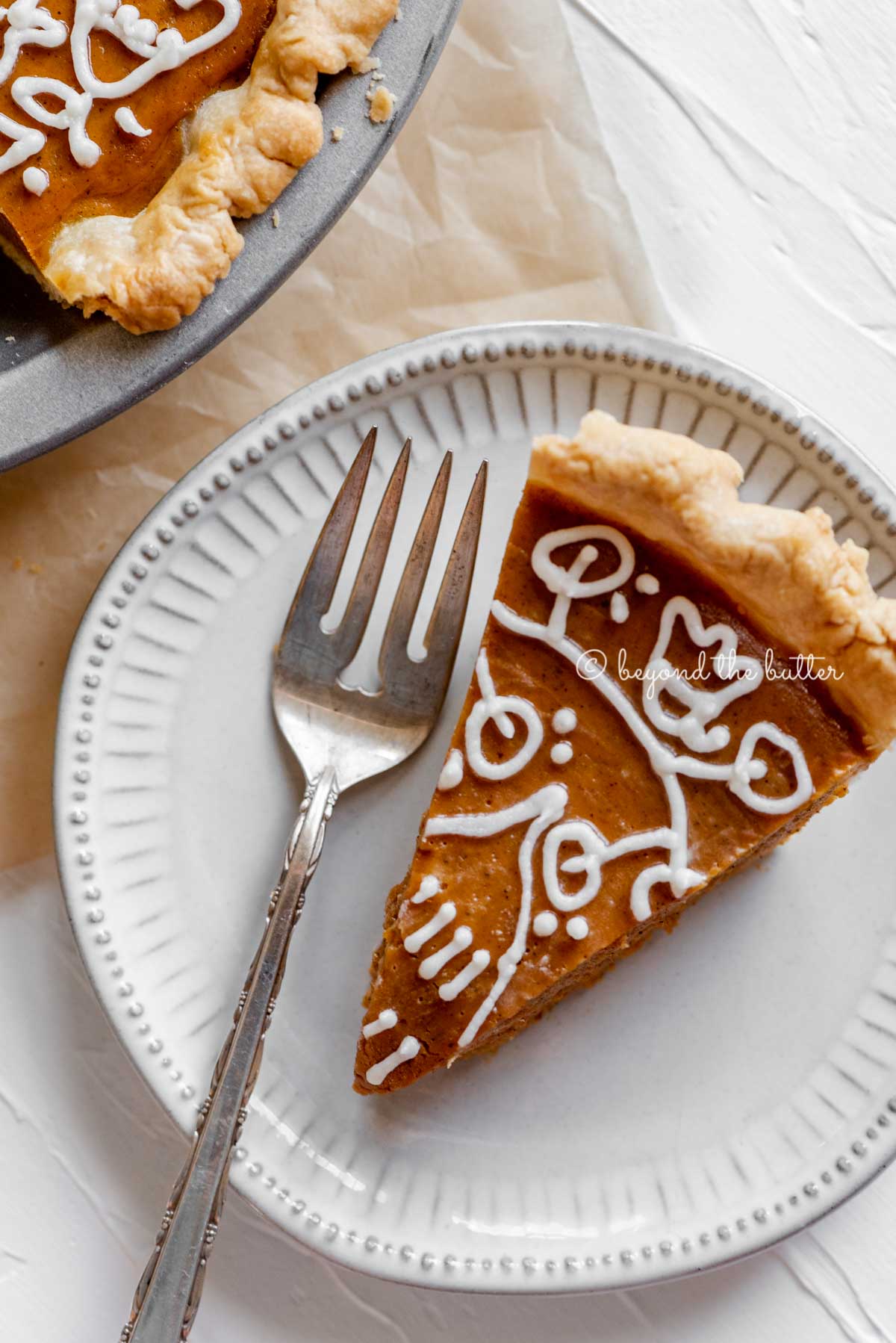 Slice of pumpkin pie on a dessert plate with a fork resting on the plate and pie plate off to the side | All Images © Luyiz™