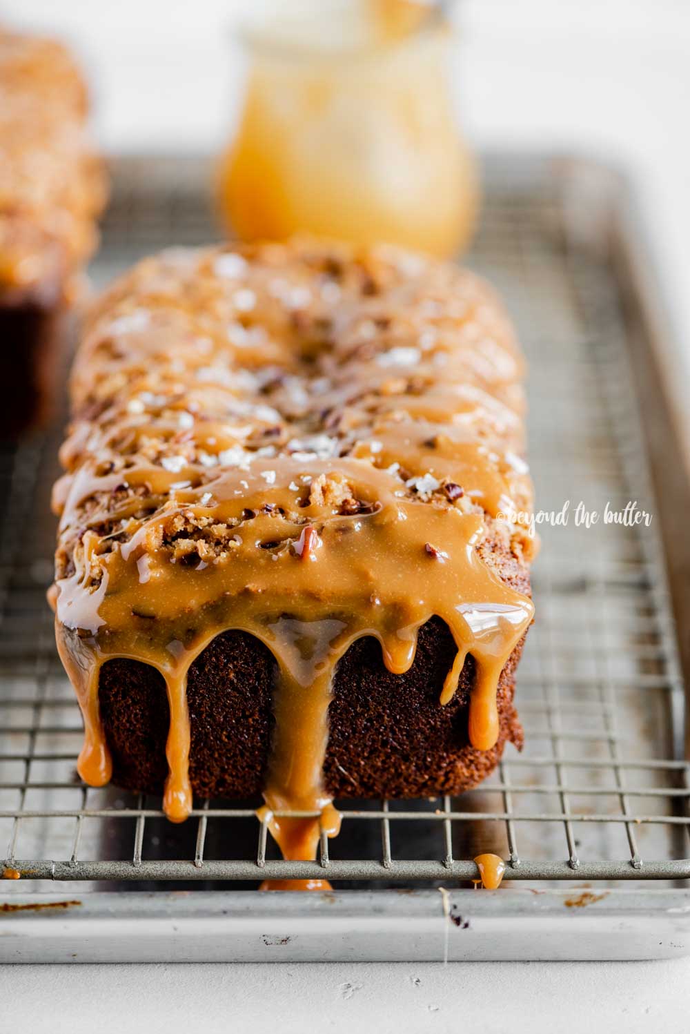 Angled image of salted caramel banana nut bread loaves on a wire cooling rack with caramel drizzled over the top | All Images © Luyiz™