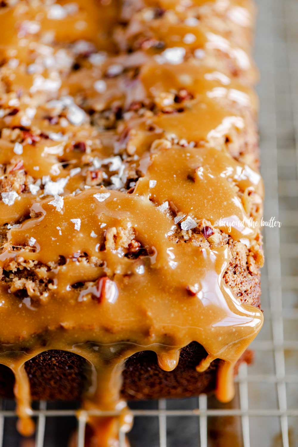 Angled image of salted caramel banana nut bread loaves on a wire cooling rack with caramel drizzled over the top | All Images © Luyiz™