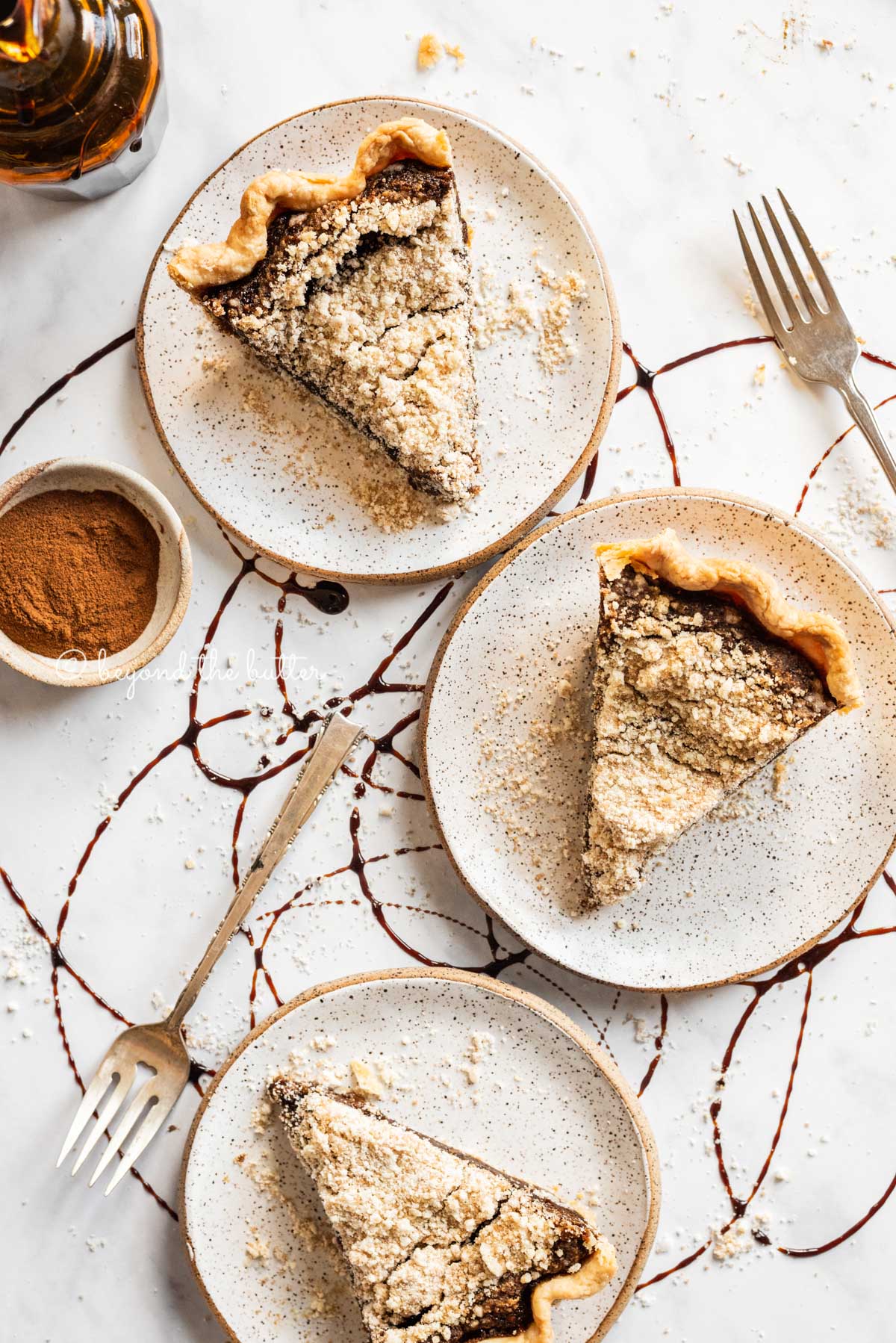 Slices of shoo fly pie on dessert plates with a bowl of cinnamon and glass of molasses | All Images © Luyiz™