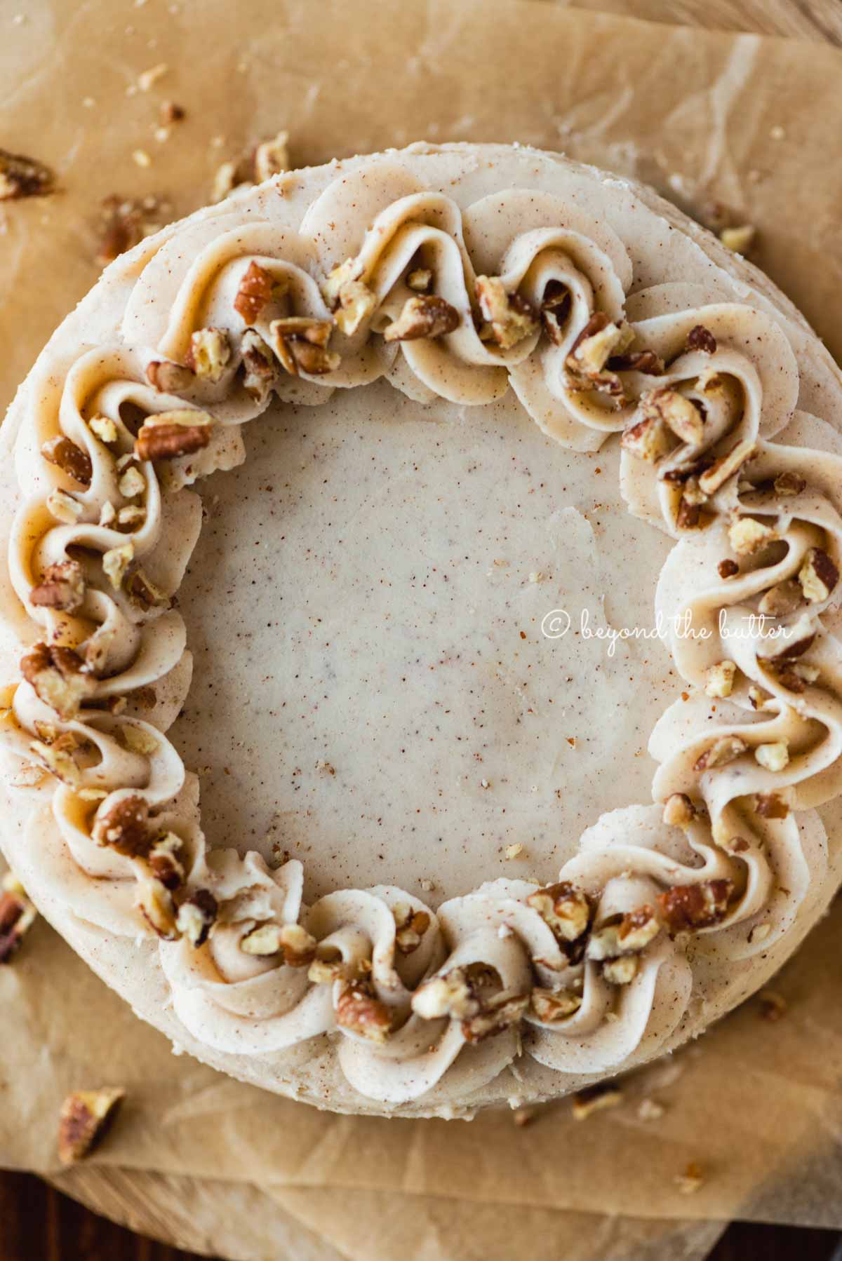 Overhead closeup image of 6 inch carrot cake frosted on sheets of brown parchment paper | All Images © Luyiz®