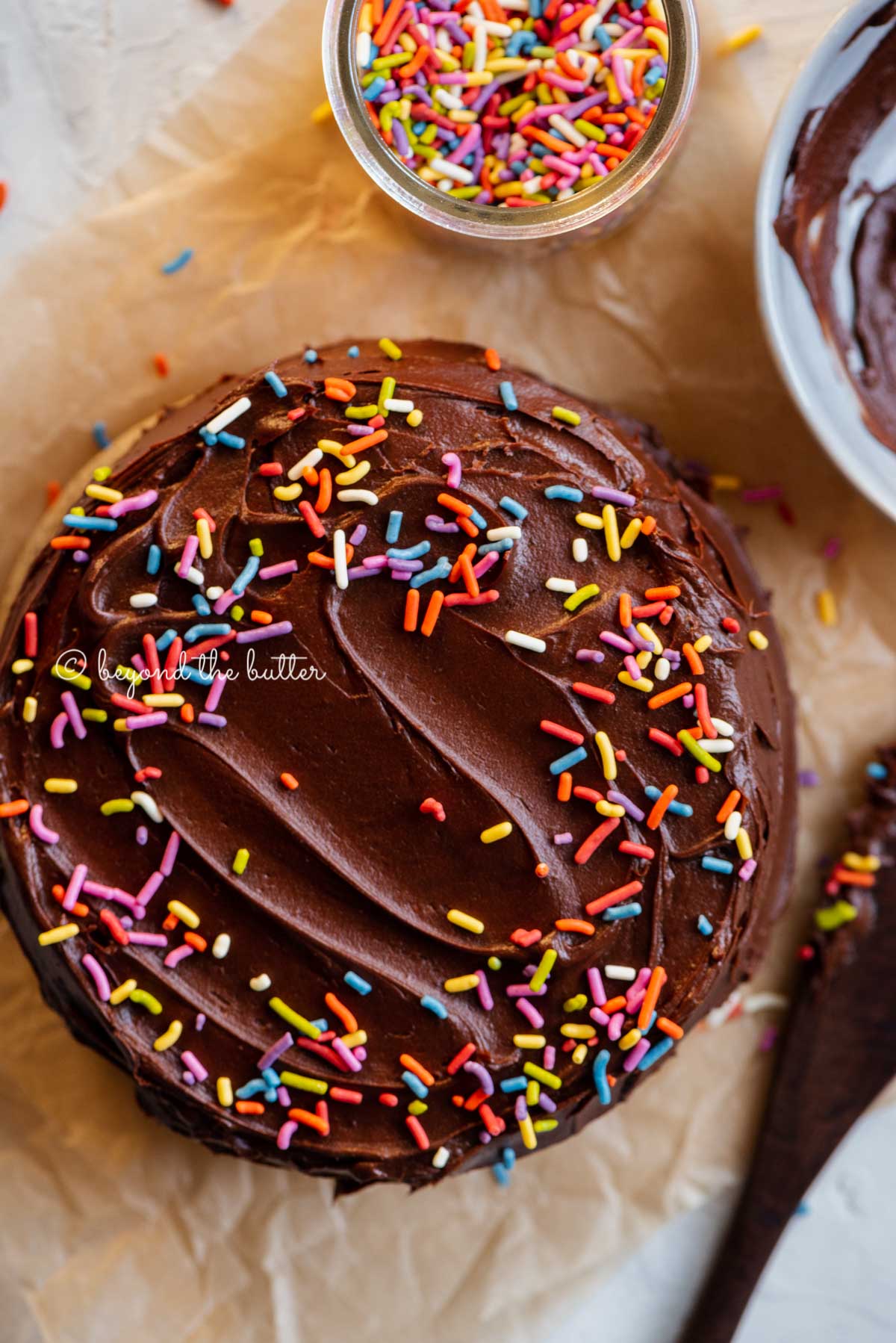 Overhead image of single layer chocolate cake with bowl of milk chocolate frosting | All Images © Luyiz®