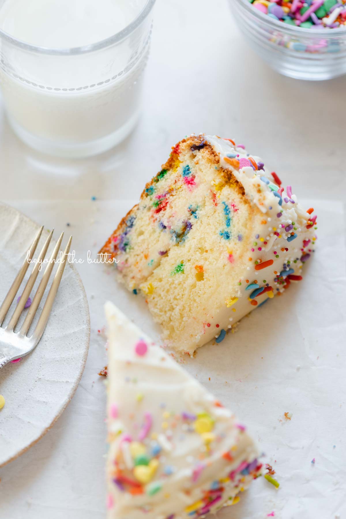 Slices of single layer funfetti cake on their side with a dessert plate, small fork, and glass of milk nearby from Luyiz | All images © Luyiz®