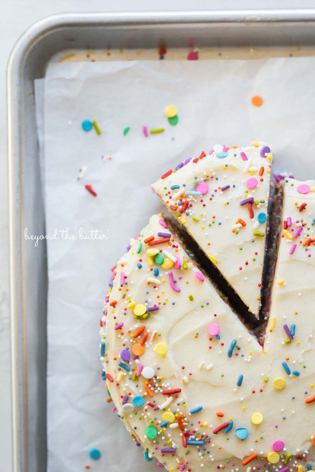 Cut slice of single layer funfetti cake partially removed from rest of the cake on a parchment paper lined baking sheet | All images © Luyiz®