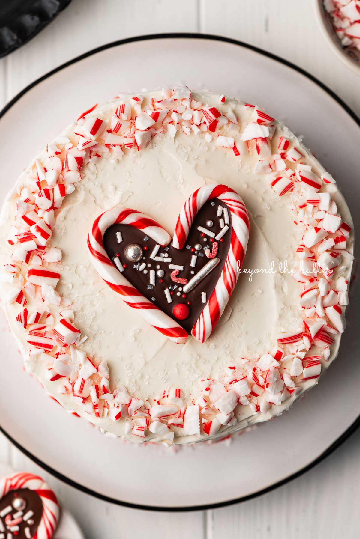 Single layer chocolate peppermint cake frosted with peppermint swiss merignue buttercream and garnished with crushed candy canes and candy cane heart | © Luyiz®