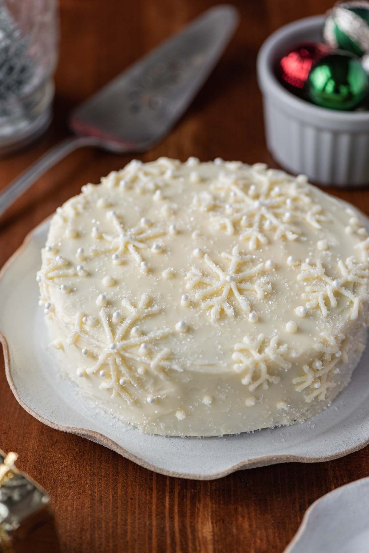 Red velvet cake with cream cheese frosting on a scalloped edge dessert plate with dark wood background | All Images © Luyiz®