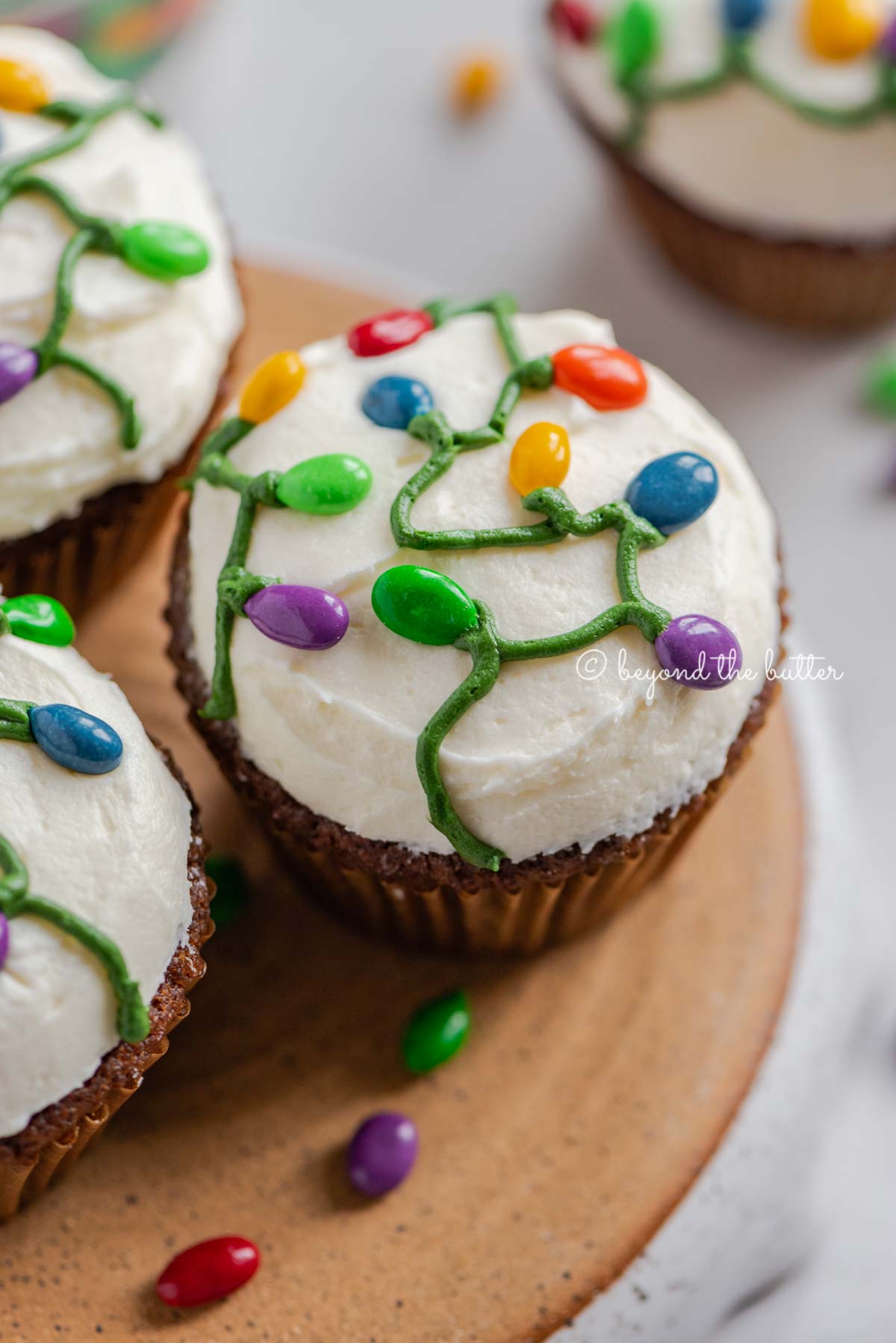 Small batch of gingerbread cupcakes on an upside down pie plate on a white background with scattered chocolate covered sunflower seeds | All Images © Luyiz®