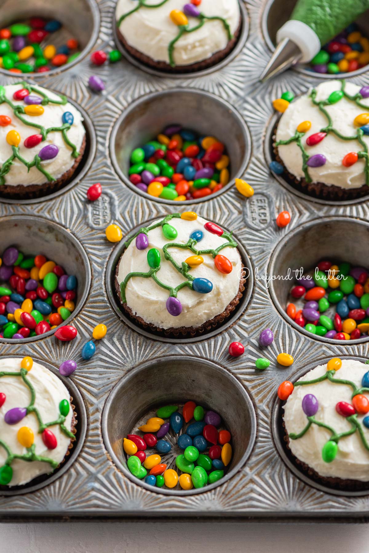 Cupcake tin with decorated small batch gingerbread cupcakes with marshmallow frosting and rainbow chocolate covered sunflower seeds | All Images © Luyiz®
