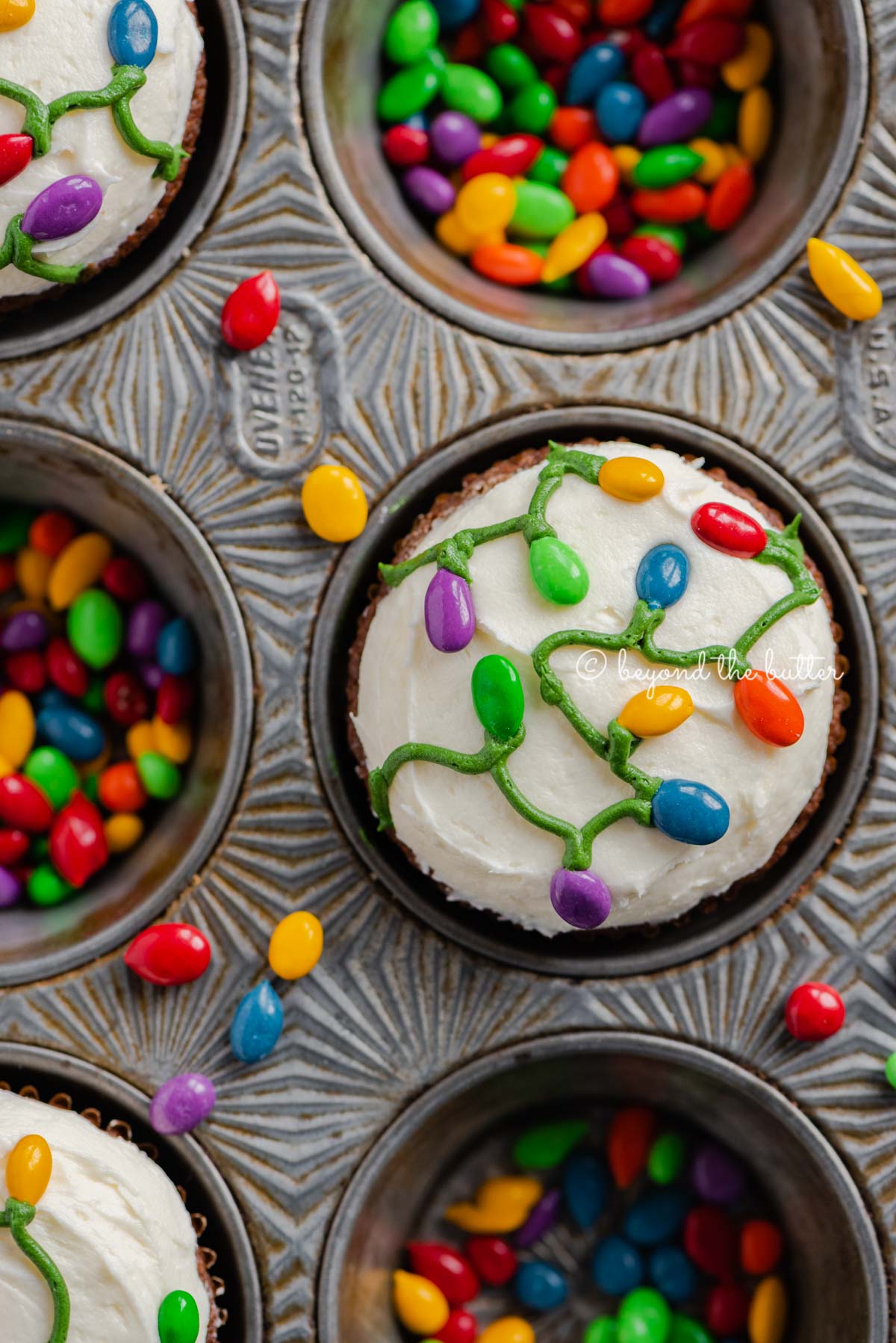 Cupcake tin with decorated small batch gingerbread cupcakes with marshmallow frosting and rainbow chocolate covered sunflower seeds | All Images © Luyiz®