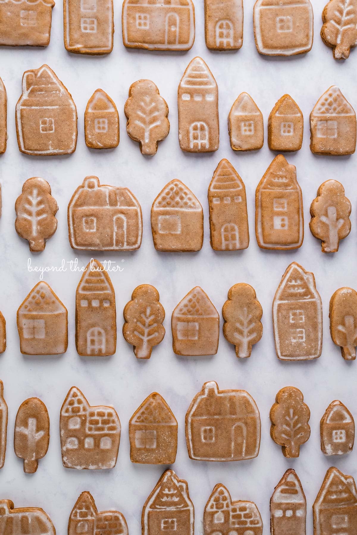 Cut out gingerbread cookies lined up in rows on a white marbled background | © Luyiz, LLC®