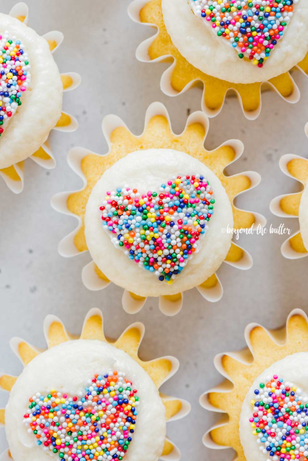 Overhead image of sprinkled heart cupcakes on white/grya background | All Images © Luyiz™