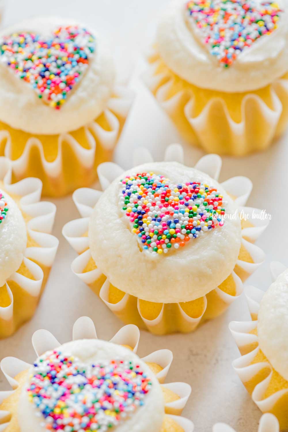 Angled image of sprinkled heart cupcakes on white/grya background | All Images © Luyiz™