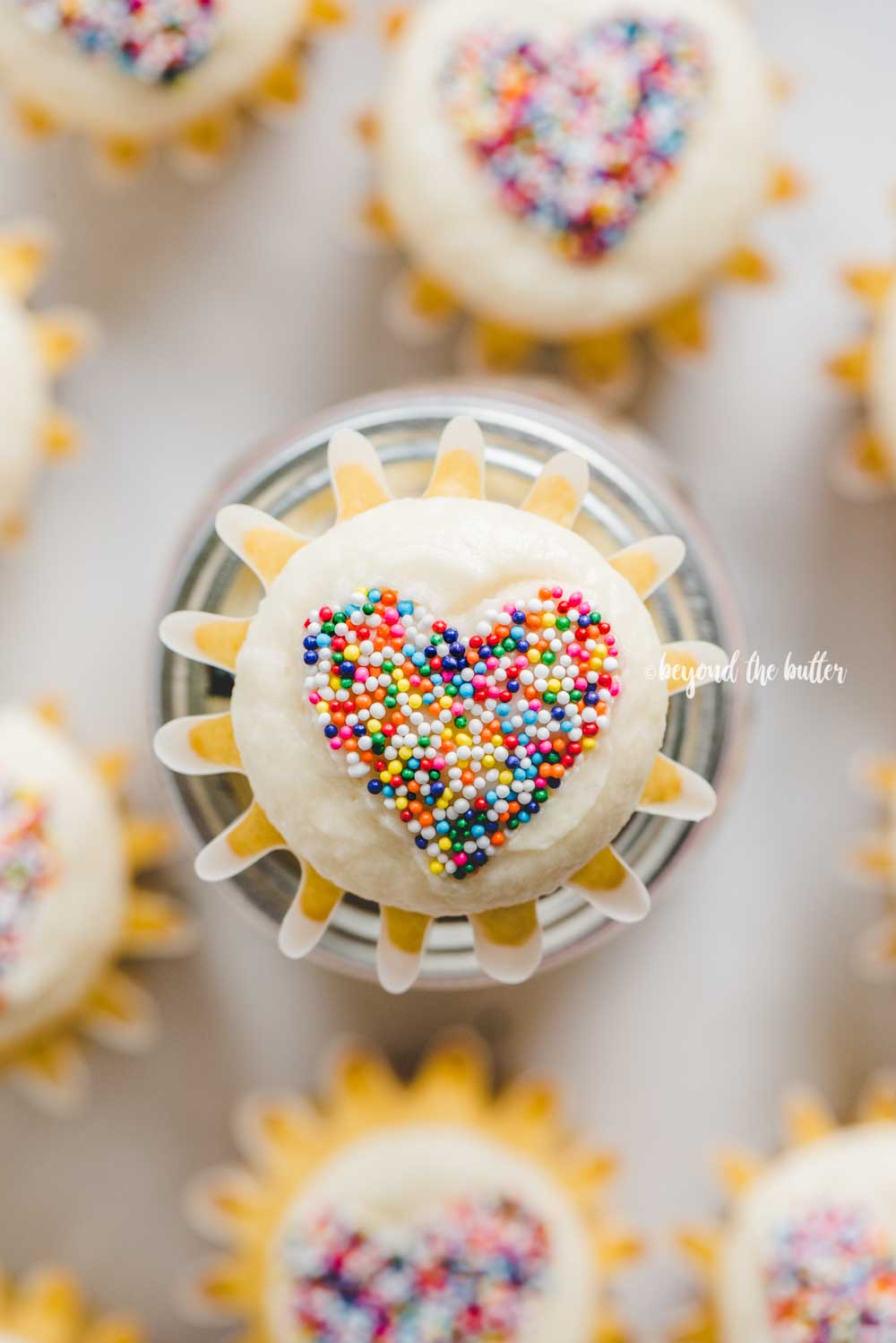 Overhead image of sprinkled heart cupcakes on white/grya background | All Images © Luyiz™