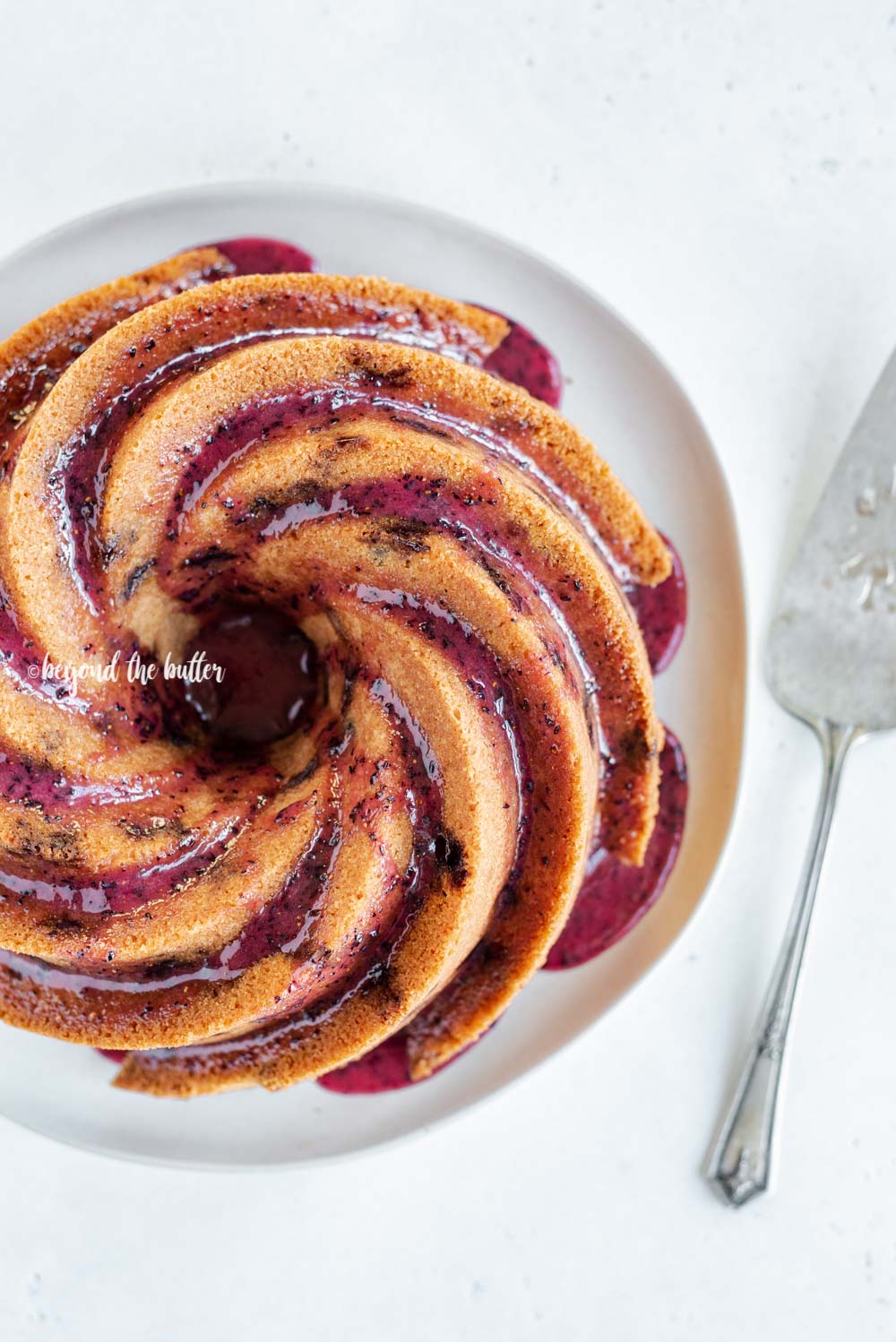 Overhead image of super easy blueberry bundt cake recipe with blueberry glaze drizzled over the top | All Images © Luyiz, LLC